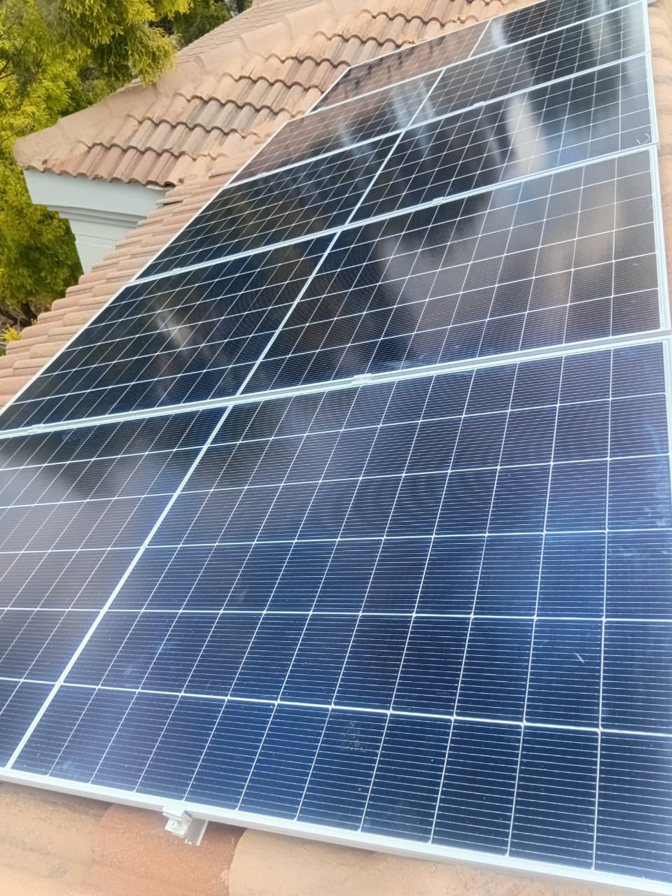 Close view of a monocrystalline solar panel array on terracotta roof tiles